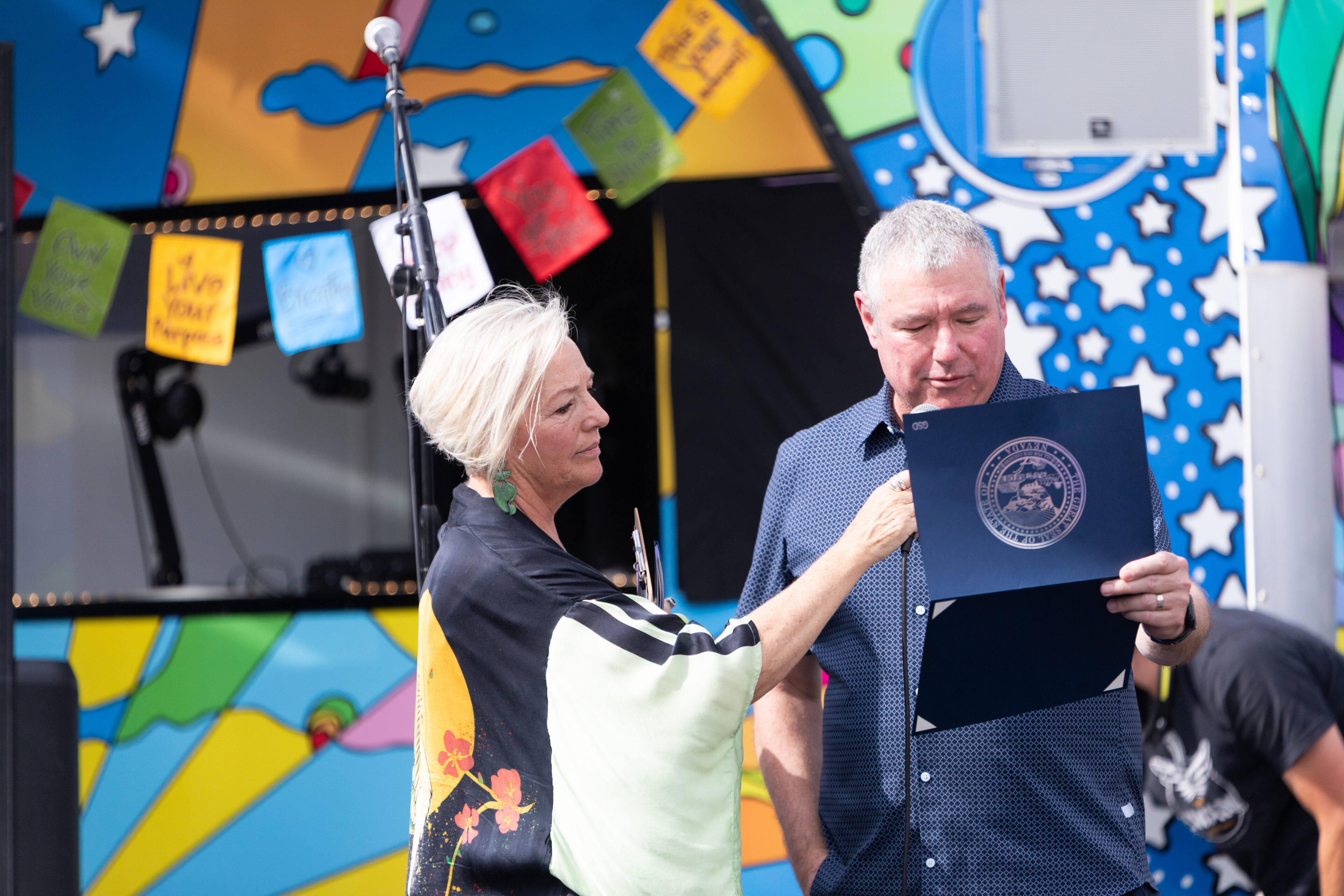 Carson Tahoe Health Board Chair Brian Duffrin reads a recognition on behalf of Nevada Governor, Joe Lombardo alongside Carson Tahoe Health Vice President of Community and Patient Experience Kitty McKay at the Dave Mason Legacy Dedication and Benefit Concert on Sunday, July 12, 2026 in Carson City, Nev. (Trevor Bexon/AP Content Services for Carson Tahoe Health)